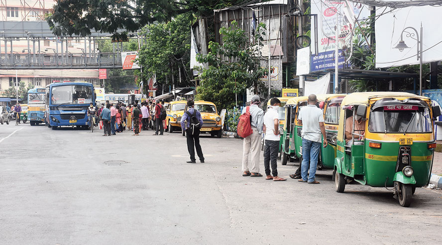Commuters await public transportation at Ultadanga crossing during the morning office hour