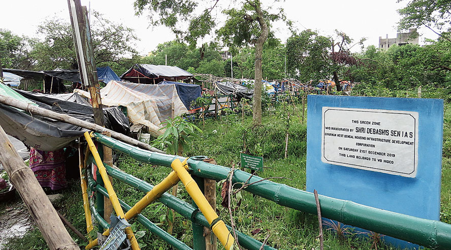 They line the bamboo fencing of an empty plot designated as a green zone in the foundation stone