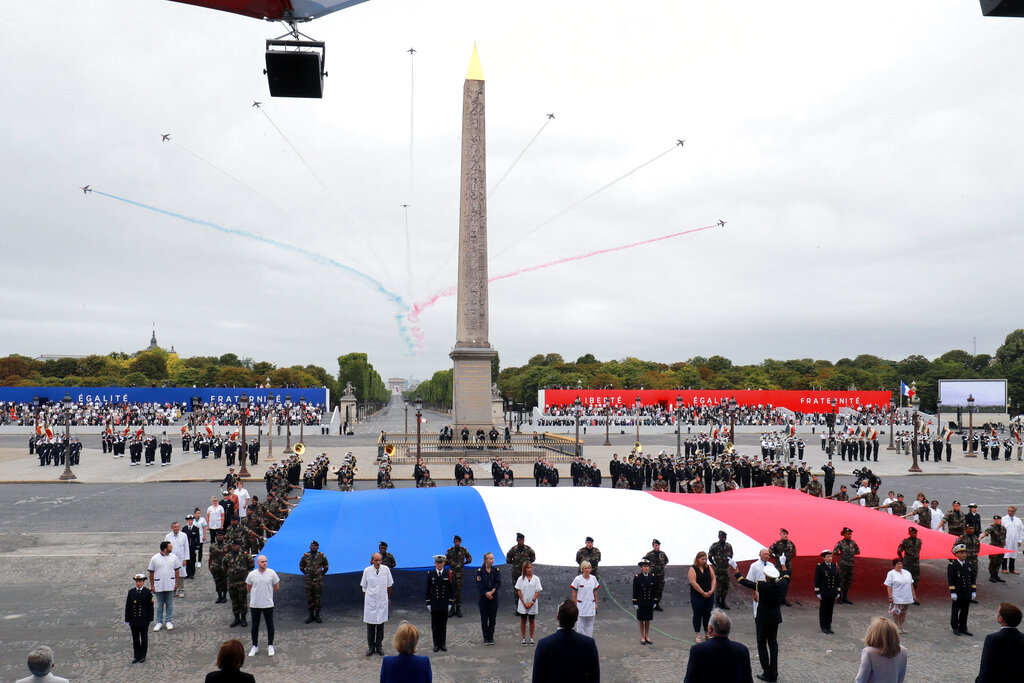 Members of medical staff pose with the French flag as they take part in the annual Bastille Day military ceremony on the Place de la Concorde in Paris, Tuesday, July 14, 2020. France are honoring nurses, ambulance drivers, supermarket cashiers and others on its biggest national holiday