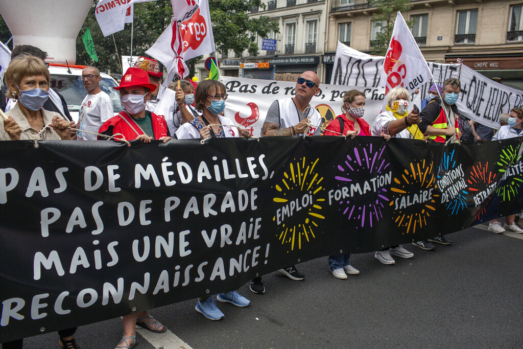 Members of medical staff pose with the French flag as they take part in the annual Bastille Day military ceremony on the Place de la Concorde in Paris, Tuesday, July 14, 2020. France are honoring nurses, ambulance drivers, supermarket cashiers and others on its biggest national holiday