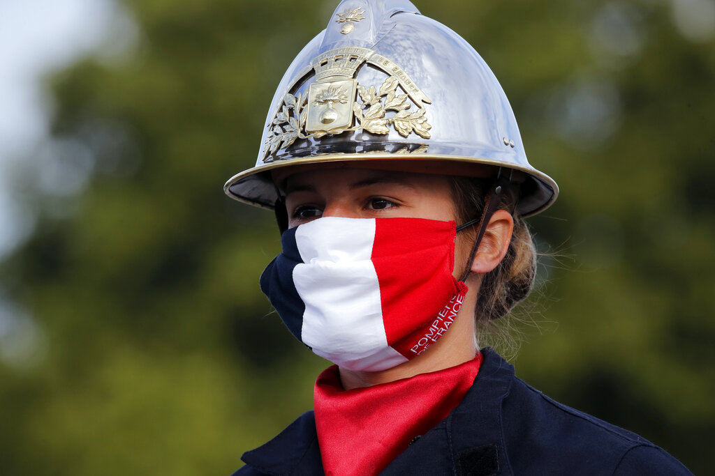 A firefighter wears a face mask with the colors of the French flag, prior to the Bastille Day parade Tuesday, July 14, 2020 on the Champs Elysees avenue in Paris.