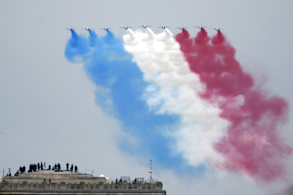 Guests watch form the top of the Arc de Triomphe the French Alpha jets of the Patrouille de France flying over the Champs Elysees avenue during the Bastille Day military parade, Tuesday, July 14, 2020 in Paris.