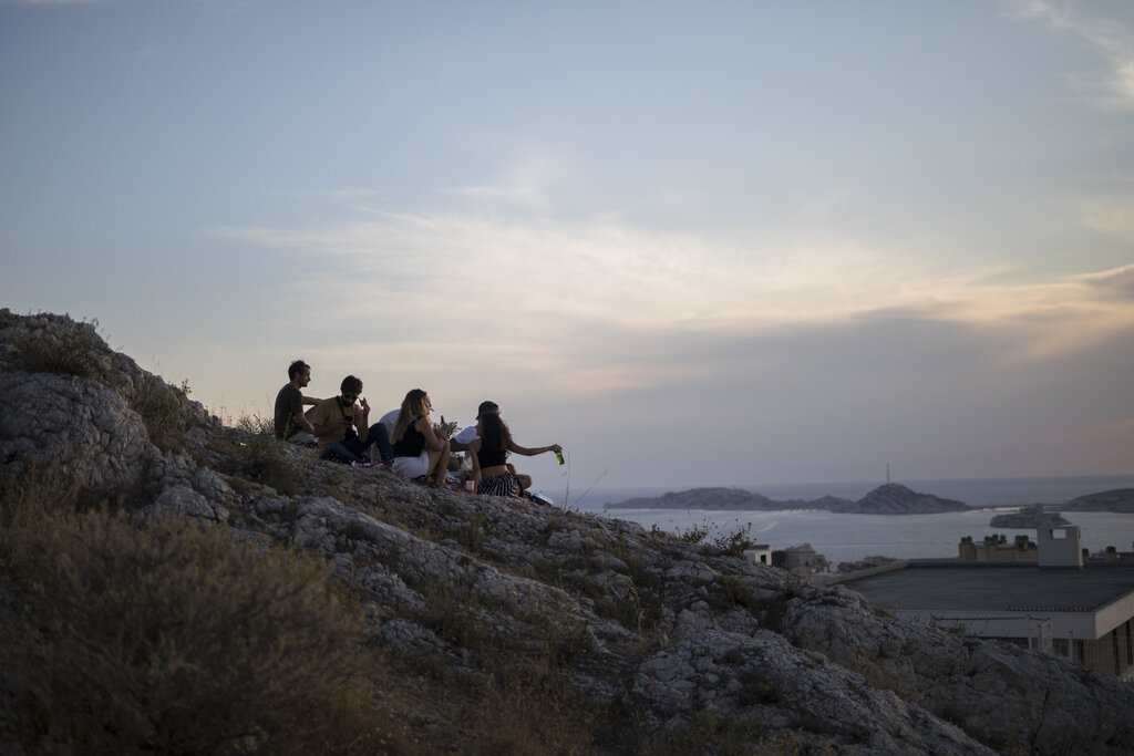 Friends share a drink and watch the sunset during Bastille Day in Marseille, southern France, Tuesday July 14, 2020. 