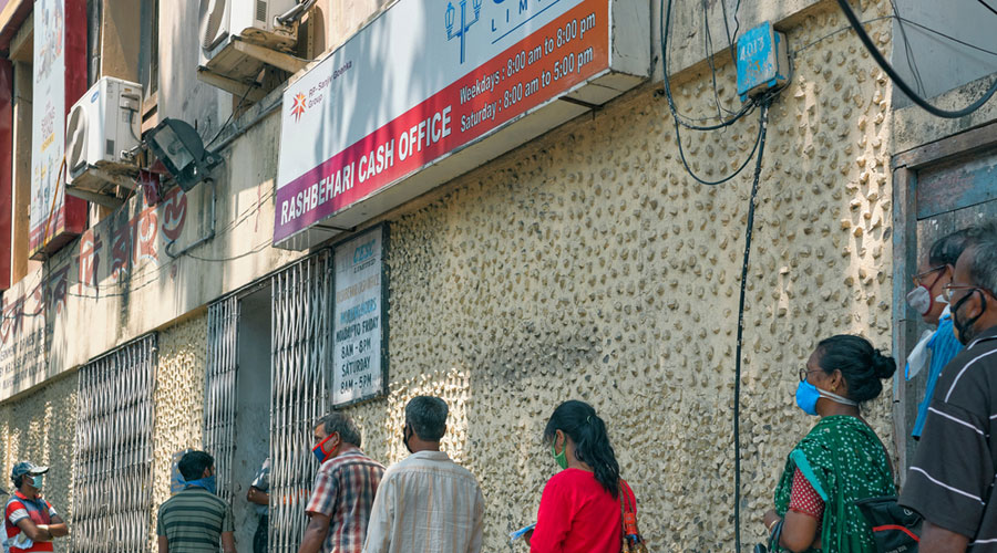 People wait in a long queue to pay monthly electricity bills in front of a CESC cash office