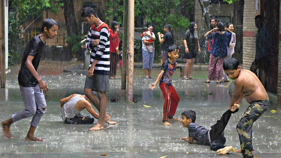 Children play in front of a temple during heavy rain in Noida on Tuesday.