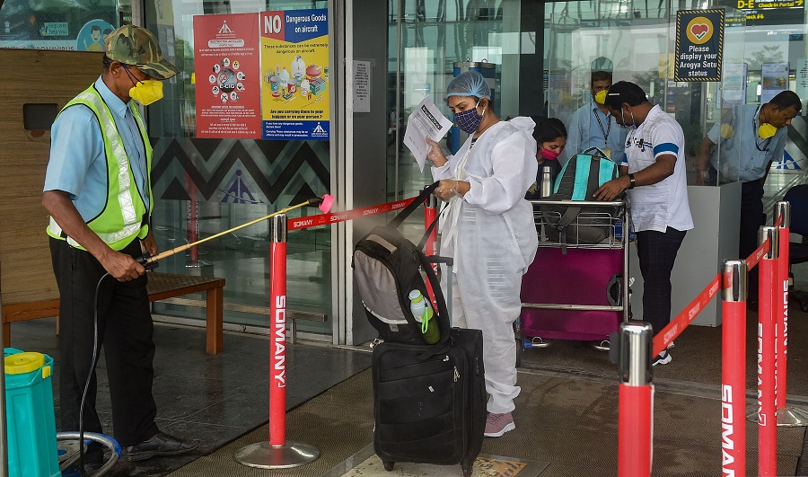 Workers sanitise passenger baggage in front of the entry gate at NSCBI Airport, during weekly two-day complete lockdown to curb the spread of coronavirus disease, in Calcutta, Thursday, July 23, 2020. 
