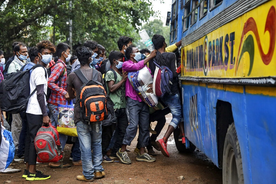 Commuters wearing face masks jostle for a ride on a bus discarding social distancing guidelines in Calcutta, Tuesday, July 21, 2020.
