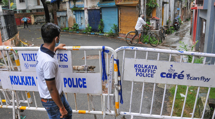 A man stands near barricades inside the sealed residential area after the state government imposed total lockdown in all containment zones following a surge in Covid-19 cases in Calcutta on Friday.