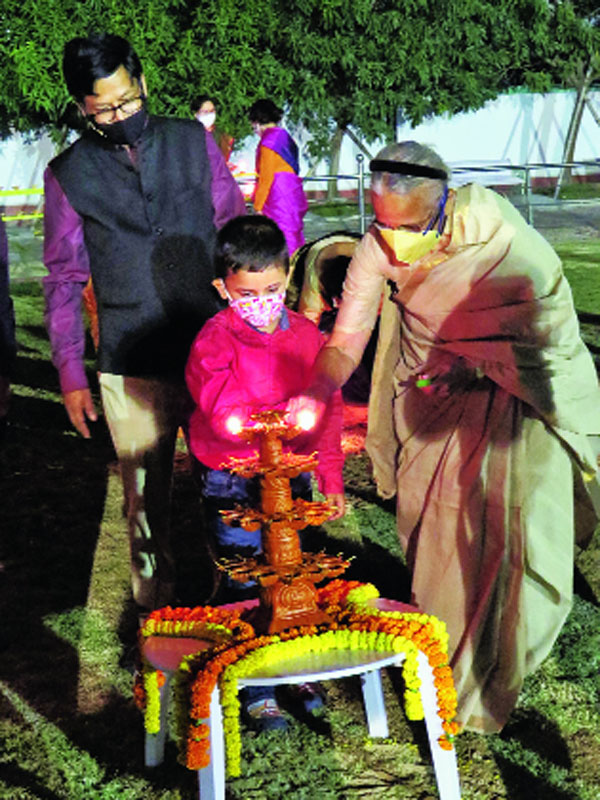 Snehodiya resident Uma Dasgupta lights the inaugural lamp along with five-year-old Ahamstuta Basu at Swapno Bhor on Kali puja night as Hidco chief Debashis Sen looks on.