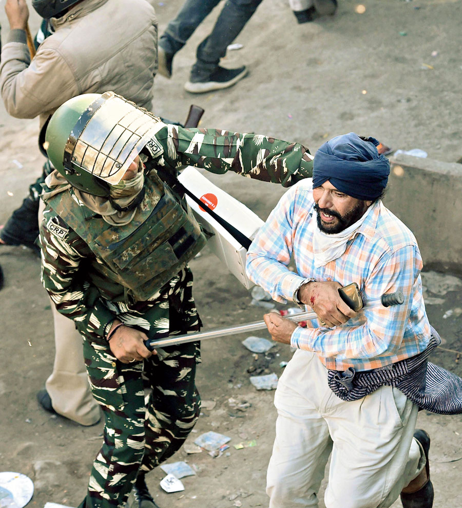 A policeman wields a baton on another farmer at Narela in New Delhi on Friday.