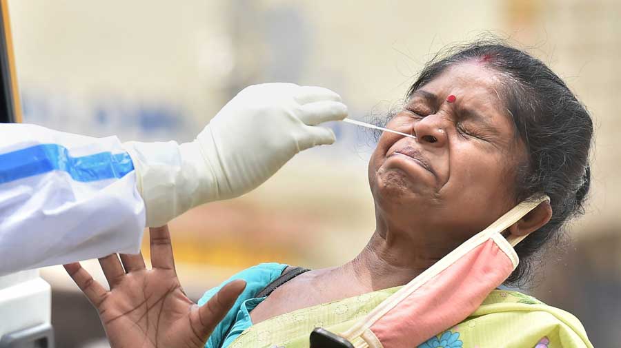A health worker collects a a woman's swab sample for a Covid-19 test in Calcutta 