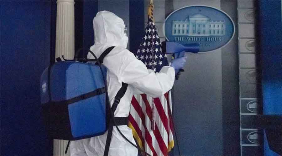 A member of the White House cleaning staff disinfects a room.