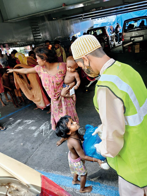 Another volunteer distributes ration to people living on the footpath near Gariathat