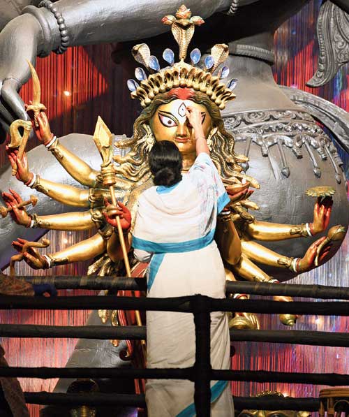 Chief minister Mamata Banerjee paints the eye of the Durga idol at the pandal of Chetla Agrani Club on Monday.
