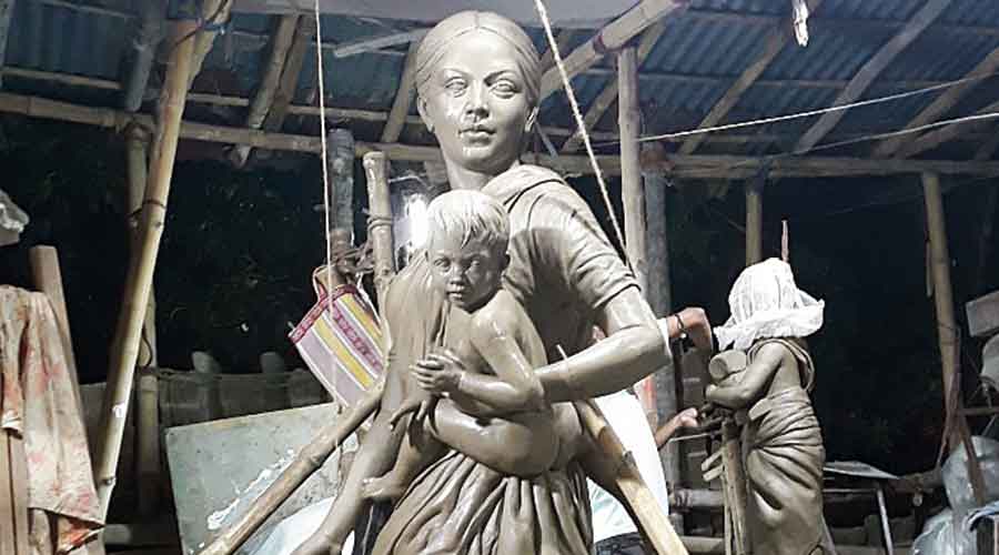 The idol of a migrant worker mother, a shirtless toddler (Kartick) in her arms at Barisha Club in Behala this year
