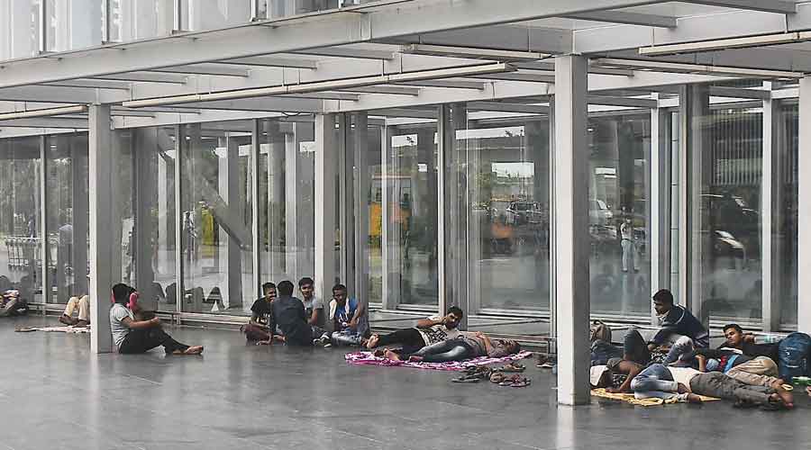 Long haul: Passengers who reached ahead of time wait for their flights outside the airport on Tuesday afternoon