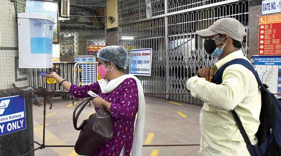 A passenger takes sanitiser from a dispenser at Dum Dum Metro station