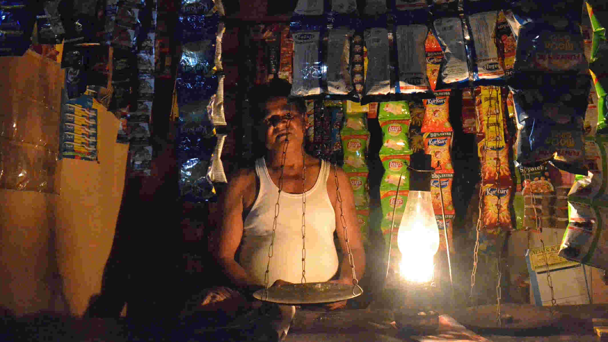 A shopkeeper is forced to use a lantern during the cut at Jharia on Sunday. 