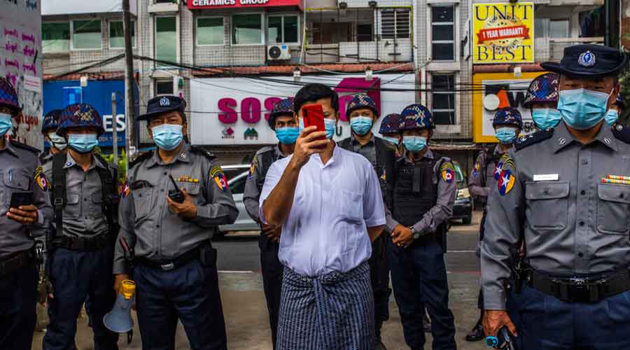 A plainclothes police officer takes a photo of journalists and protesters in Yangon, Myanmar