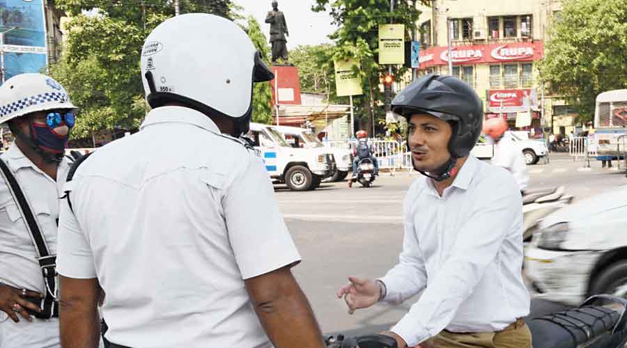 A policeman stops a motorcyclist without a mask at the Park Circus crossing on Saturday