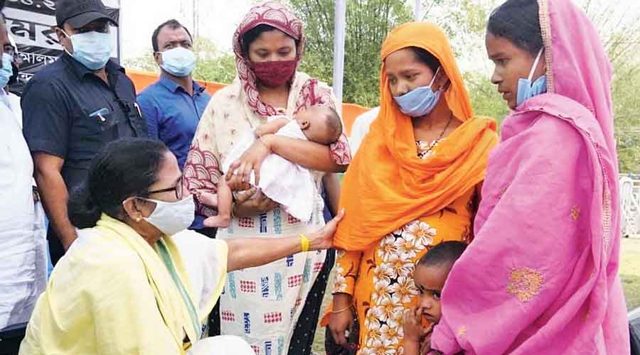 Mamata speaks to the bereaved wife of Hamidul Mian (in orange dupatta) as her  three-and-a-half-year-old daughter stands beside her in Mathabhanga on Wednesday.  To her left is Maniruzzaman Mian’s wife with her infant daughter. 