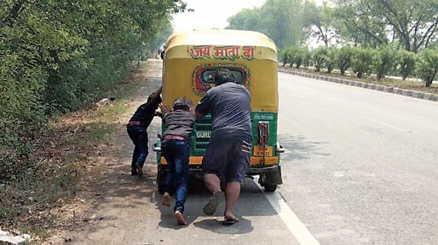 Autorickshaw driver Suresh Kumar Mahto and his family members push the vehicle after it developed a snag near Basti in Uttar Pradesh on Wednesday