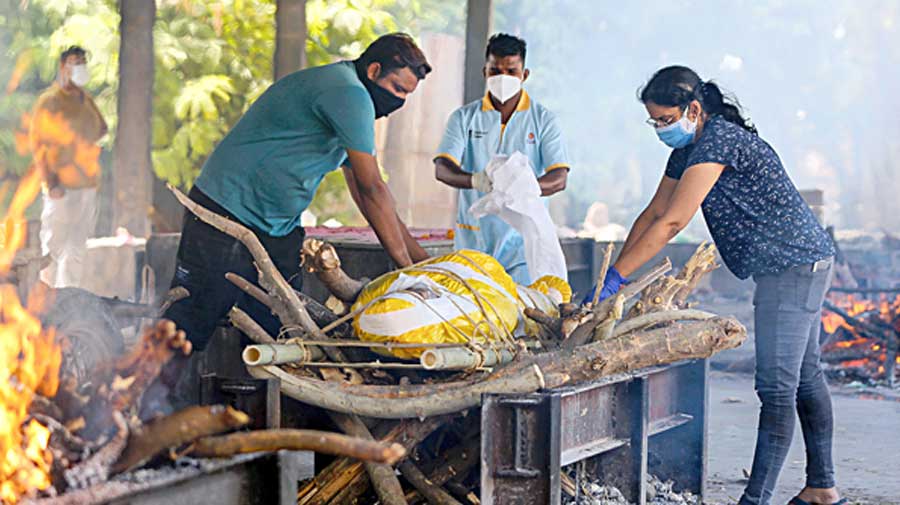 Relatives perform the last rites of a Covid-19 victim as  other pyres burn around them at a crematorium in Ahmedabad on April 19. 