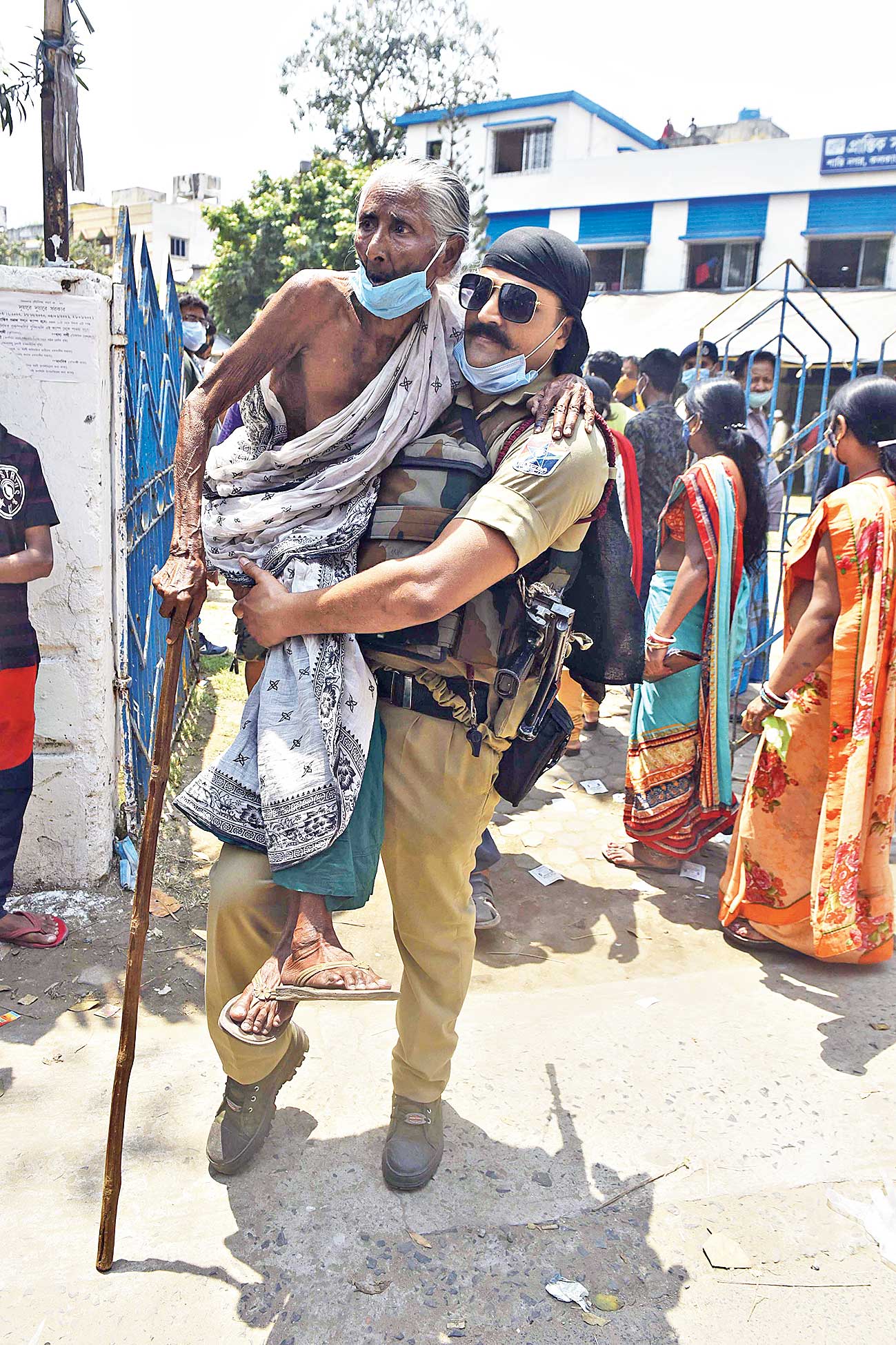 A central force jawan carries an old lady into Prantik Samaj Sadan at Shantinagar in the Sukantanagar area on election day on Saturday