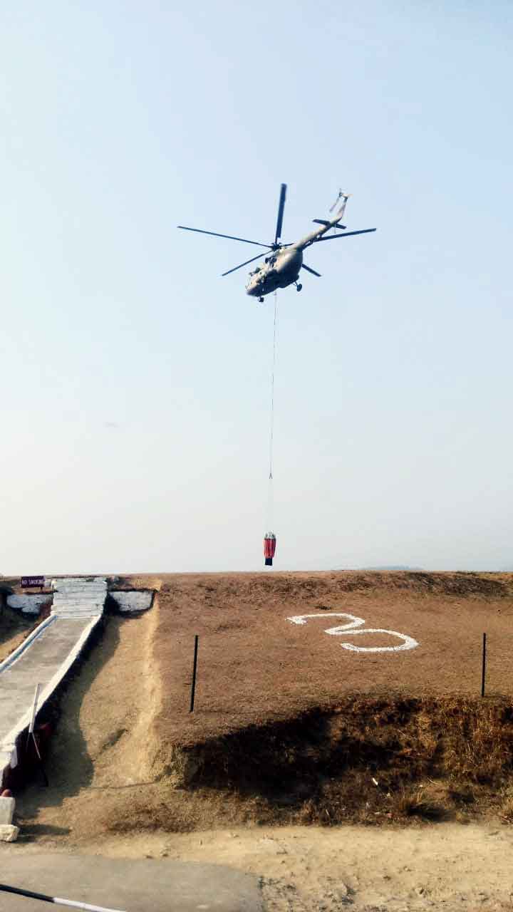 An IAF chopper with a bambi bucket joins the  dousing operation in Lunglei district on Monday