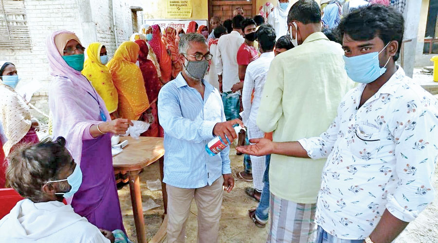 Hand sanitiser being provided to a voter at a polling station in the Ratua Assembly constituency of Malda on Monday.