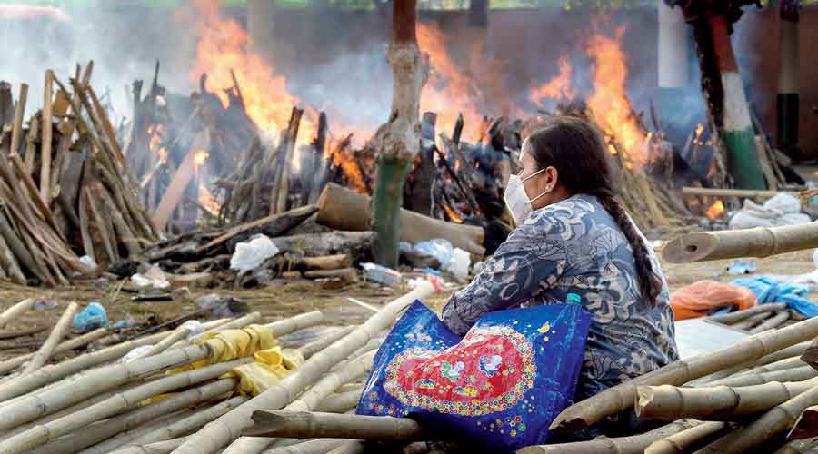 A woman watches the pyres burn at the Ghazipur crematorium in  New Delhi on Monday. 