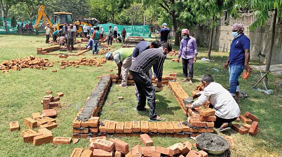 Workers constuct chambers for cremation at a park near  Sarai Kale Khan in New Delhi on Tuesday