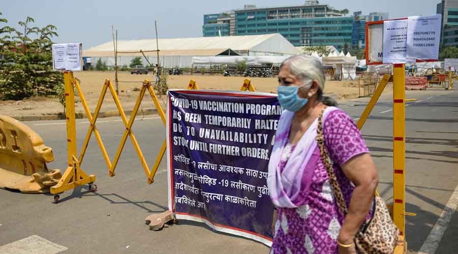 A woman stands behind a barrier outside a vaccination centre as vaccination stopped due to shortage of supplies in Mumbai
