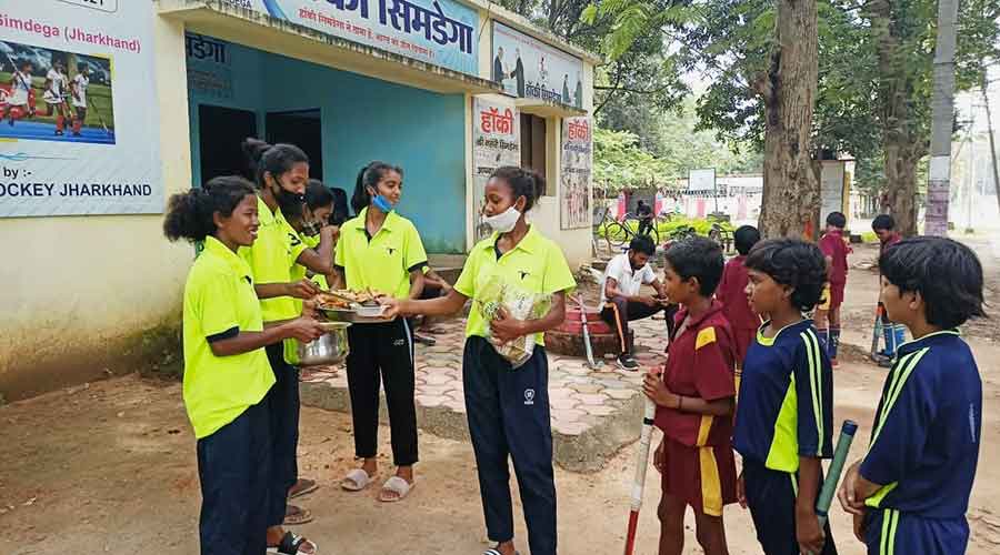 Simdega hockey players distribute sweets among locals.