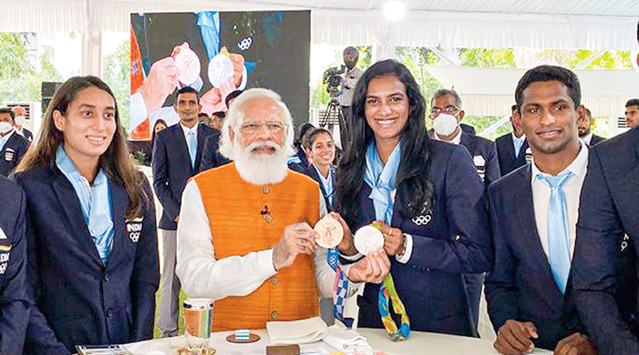 Star shuttler PV Sindhu shows her two Olympic medals — the bronze she won at the Tokyo Games and the silver she clinched at the Rio Olympics — to Prime Minister Narendra Modi during the breakfast hosted by him for all the Olympic-returned athletes at his residence in New Delhi on Monday.