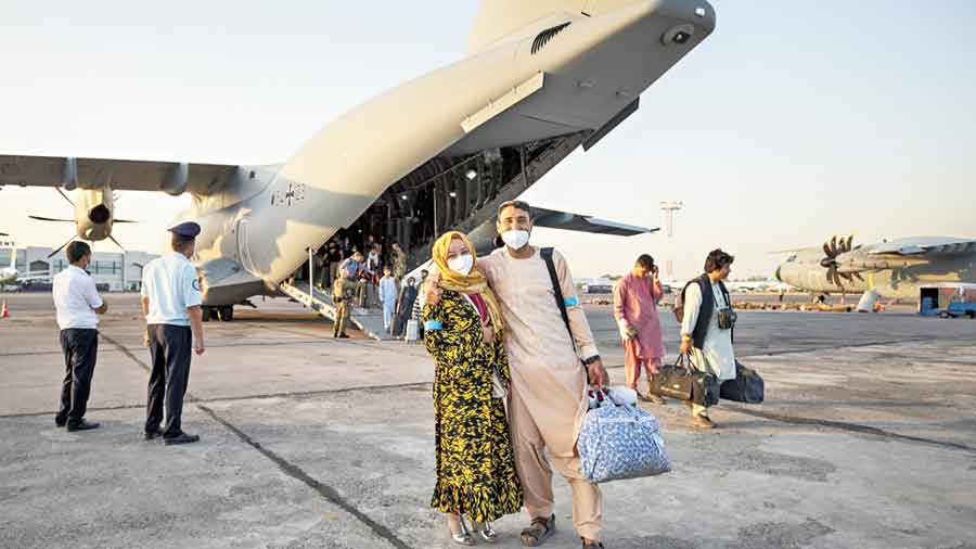 A couple evacuated from Afghanistan pose in front of a German plane after arriving in Tashkent, Uzbekistan. 