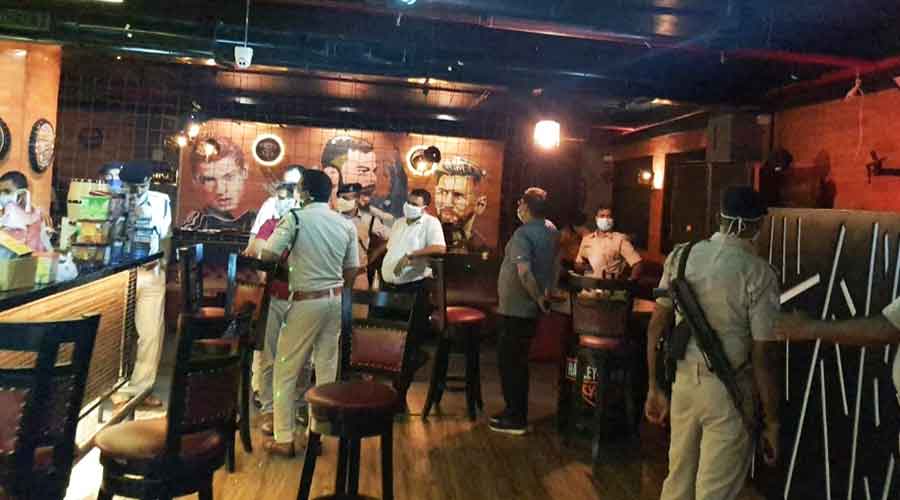 Police and administrative officials carry out the raid at a bar in Sonari on Thursday. 