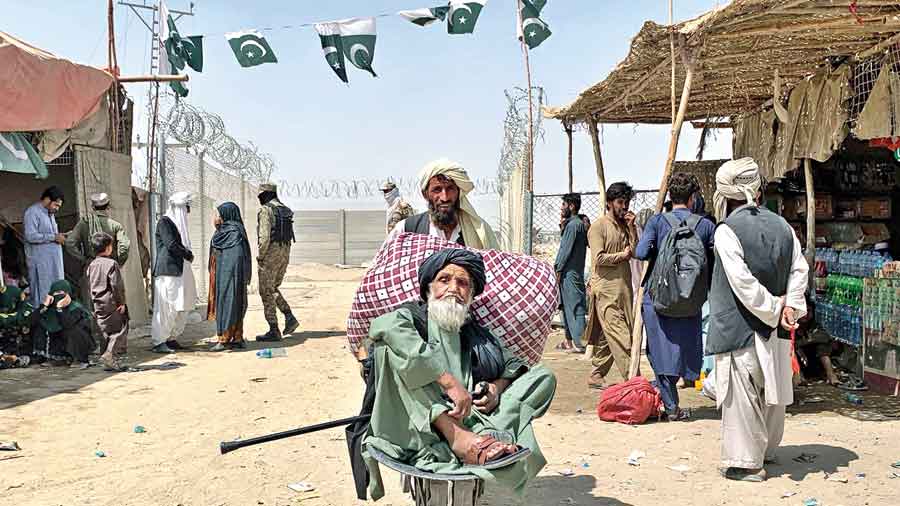 A porter pushes an elderly Afghan man in a wheelbarrow at the Chaman, Pakistan, border crossing on Friday. 