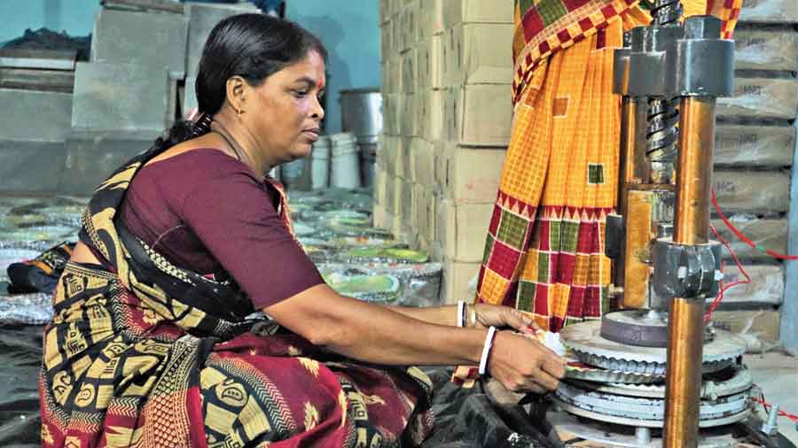 A woman works at the paper plate manufacturing unit