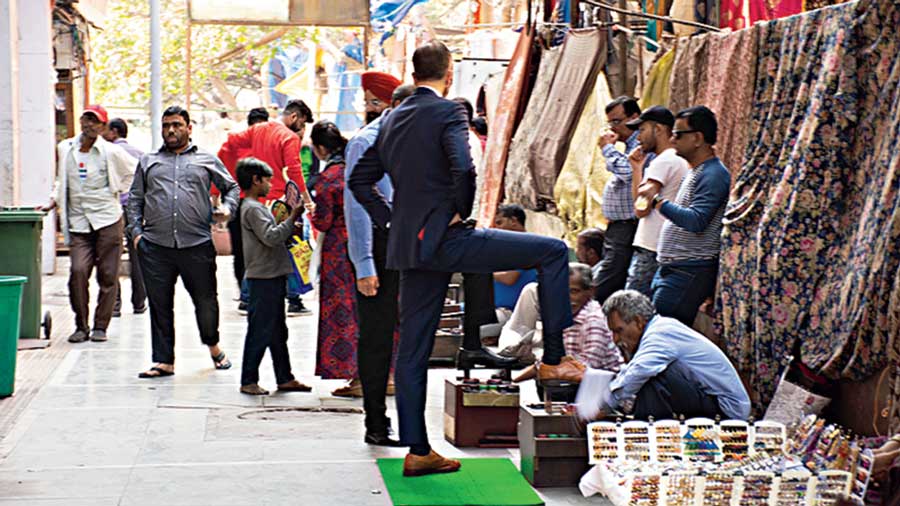 A man getting his shoe shined at Khan Market, Delhi.
