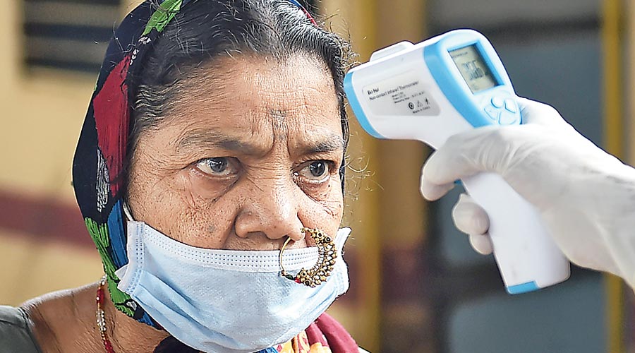A passenger’s temperature is checked at Dadar railway station in Mumbai on Tuesday.