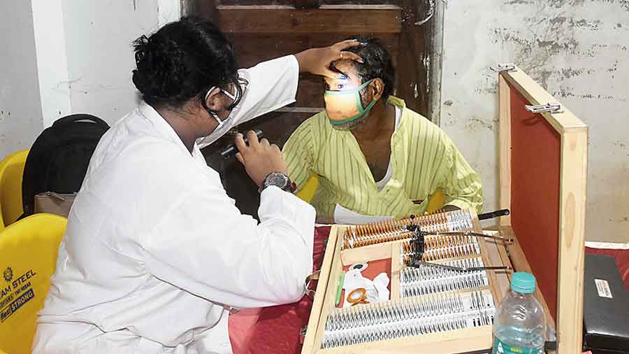 A doctor checks a patient’s eyes at Hajra Kali Mandir  grounds.