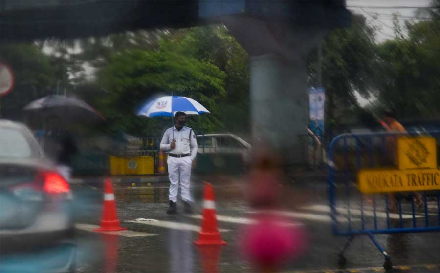 A traffic cop stands vigilant near Chingrighata crossing, Bypass. Persistent showers which have continued since Sunday morning may induce traffic snarls in the city