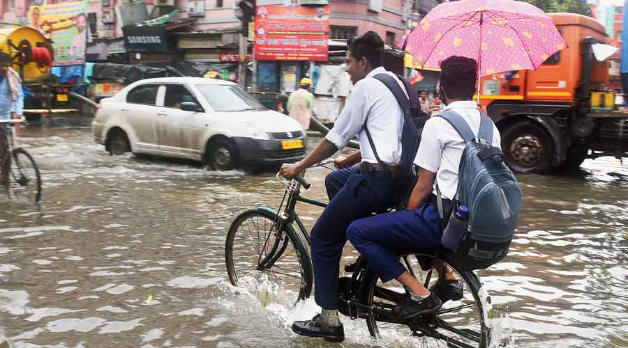 Students cycle through a flooded College Street in north Kolkata on Monday. 