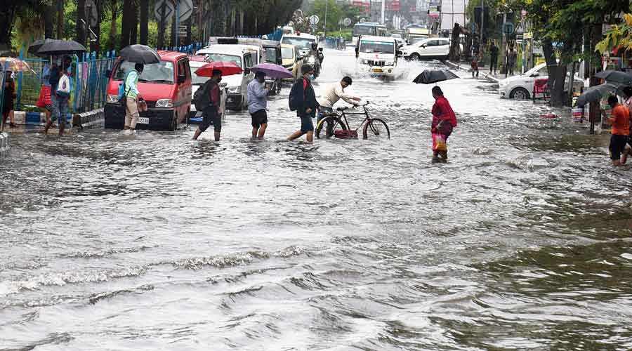 Commuters wade through a waterlogged VIP Road near Haldiram’s on Monday morning.