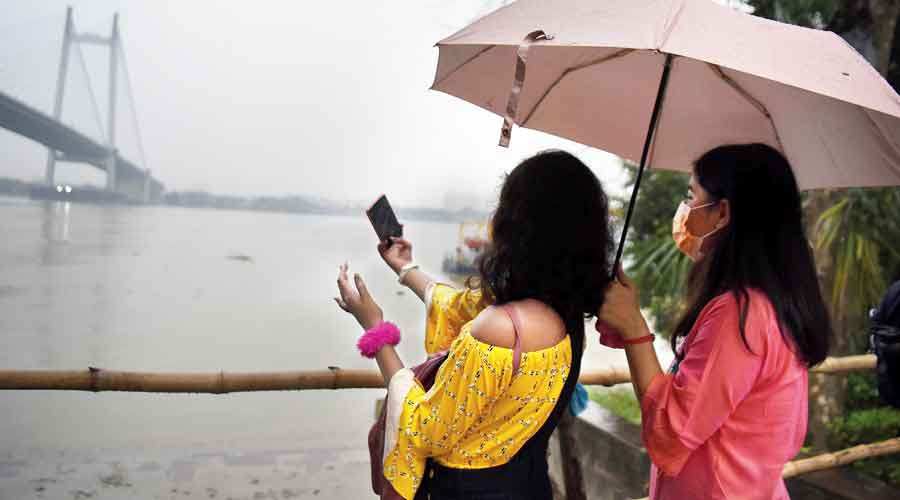 Visitors to Prinsep Ghat pose for a selfie amid rain on Thursday afternoon.