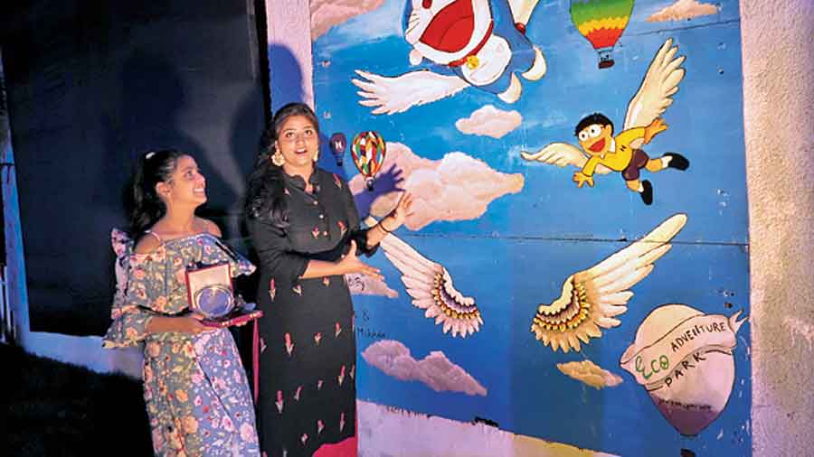 The two resident sisters Tripti Kumari and Mokshoda who have painted a section of the wall as a selfie zone with cartoon figures