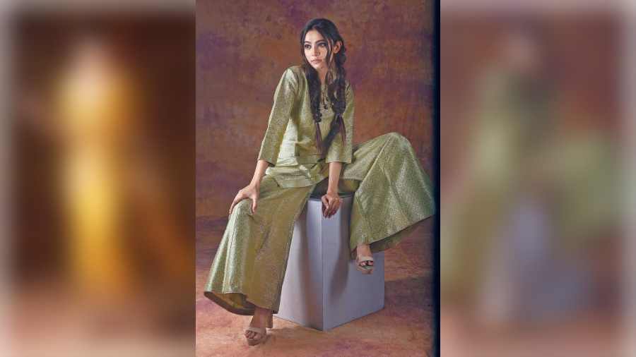 Diti sports a smart, easy-breezy occasion look in this Karwa silk palazzo and short kurta in a muted tone of brocade. The styling is inspired from the natives of Ladakh. The hair is tied in double braids and the make-up is kept minimal in nude shades. “Ladakh that has an influence of Tibetan culture uses a lot of brocade pattern and weave. The colour palette is inspired from the view (inset) outside my tent camp,” added Pinki.