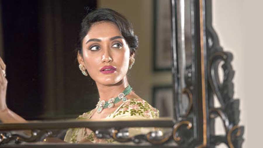Tanisha posed for a dreamy engagement look in this pastel palette. The neckpiece made of emerald beads and gold is studded with diamonds, pearls, uncut emeralds paired with a matching ring, from MP Jewellers. The hair tied back with a vintage appeal and the make-up classy with contrasting shades complete the beige-and-pastel green sari from Estri. “The earliest Indian wedding jewellery traditions had necklace sets made solely out of gold but now, the designs have extended to modern ones with diamonds, gemstones, pearls and even coloured semi-precious stones. When selecting jewellery, most brides choose to wear one or more of the four precious gemstones — diamonds, sapphires, rubies and emeralds. They’re not only gorgeous and durable but also incredibly meaningful. Each precious gemstone carries a meaning that’s as unique as its beauty and history. Precious gemstones are timeless. Bridal jewellery can be a bit of an investment,” said Soumik Roychoudhury, director, MP Jewellers.