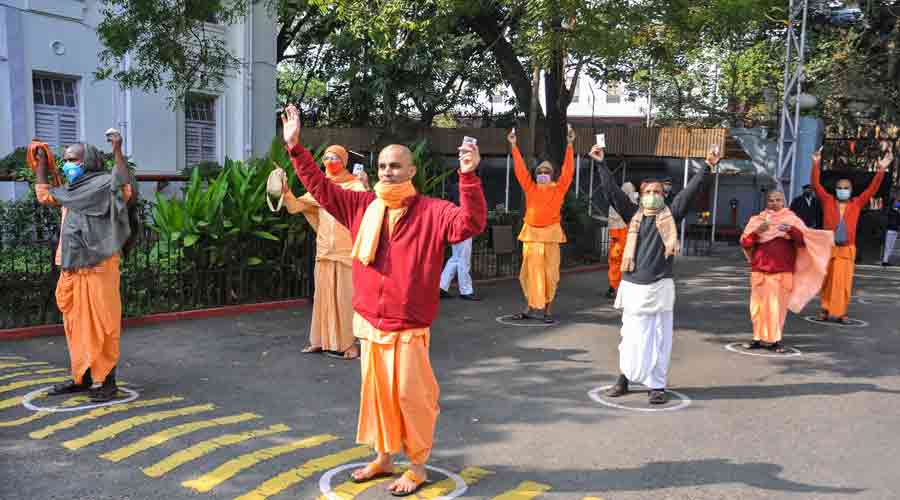 ISKCON) monks wait outside a polling booth to cast their vote during Kolkata Municipal Corporation elections, in Kolkata, on Sunday.